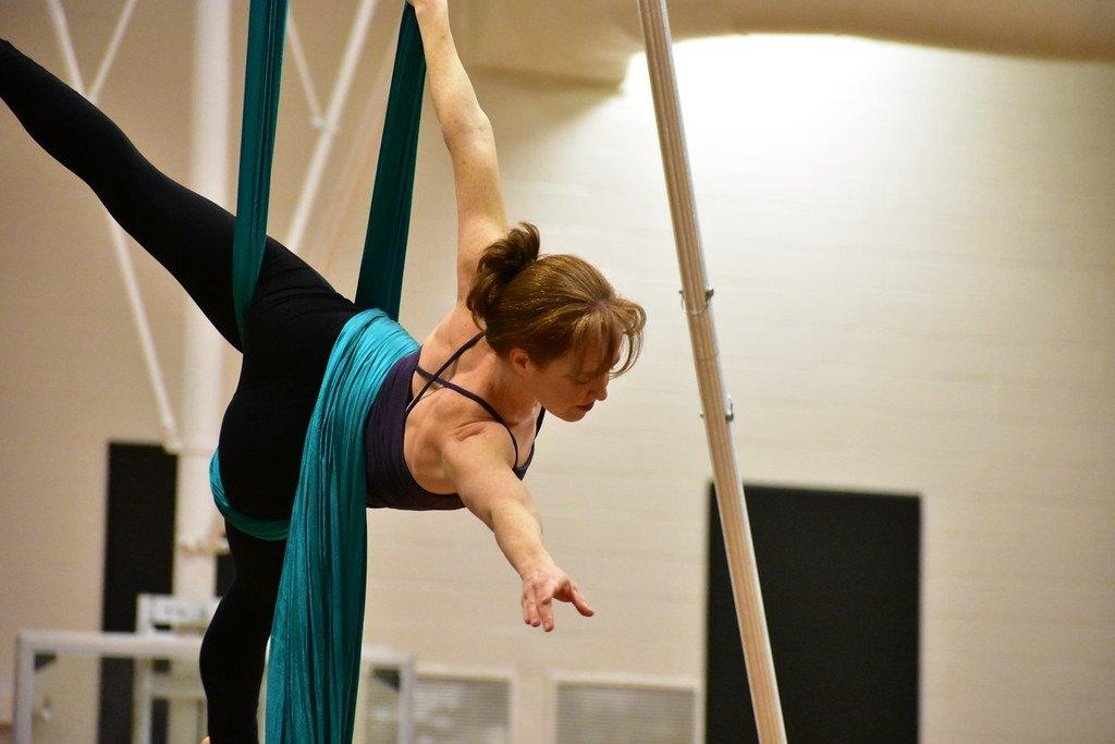 Mujer practicando en telas aéreas, con el fondo del estudio desenfocado